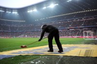 Fussball 1. Bundesliga, Saison 2011/2012:  Die Werbeflaechen auf dem Boden werden mit einem Besen gereinigt