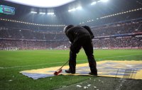 Fussball 1. Bundesliga, Saison 2011/2012:  Die Werbeflaechen auf dem Boden werden mit einem Besen gereinigt